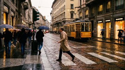 A man crossing a rainy street at dusk with reflection