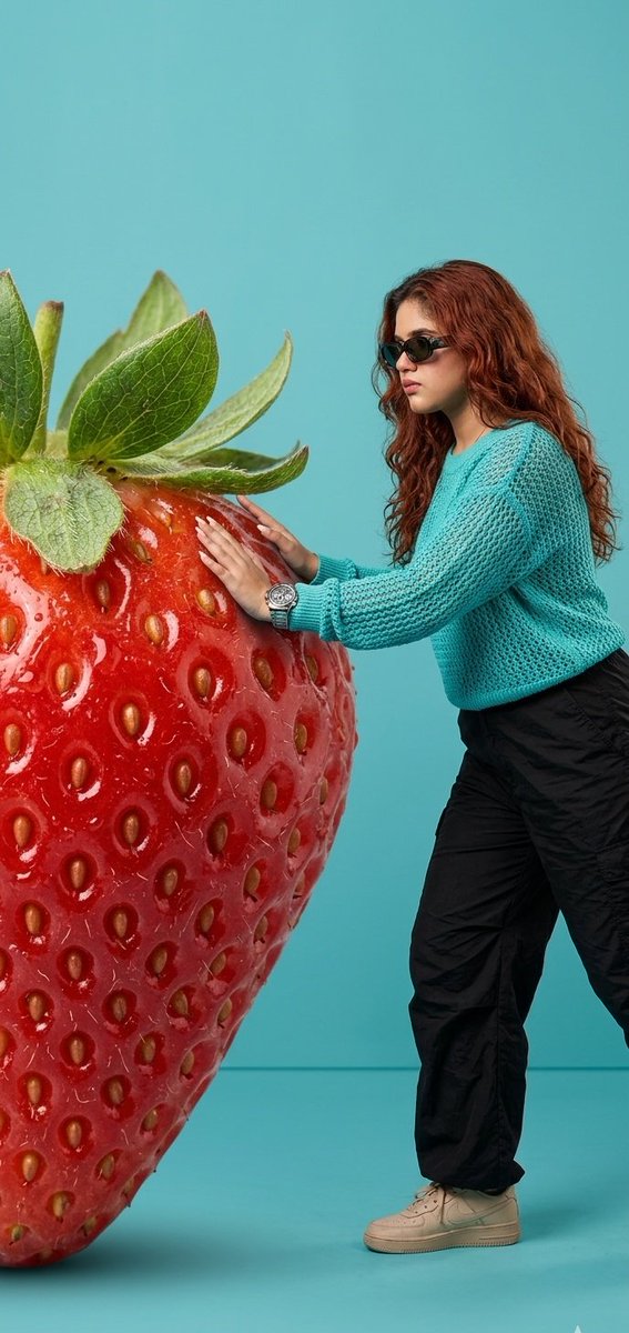 Strength Meets Surrealism: Woman Pushing a Giant Strawberry