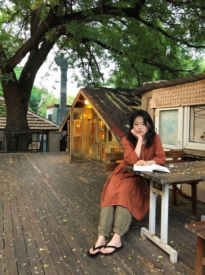 Young Woman Reads Open Book on Wooden Bench Outdoors
