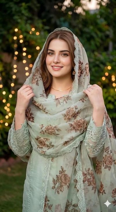 Young woman in mint green outfit smiles amid glowing garden lights