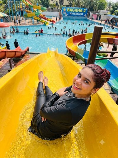Young woman slides down a yellow water slide on a sunny day
