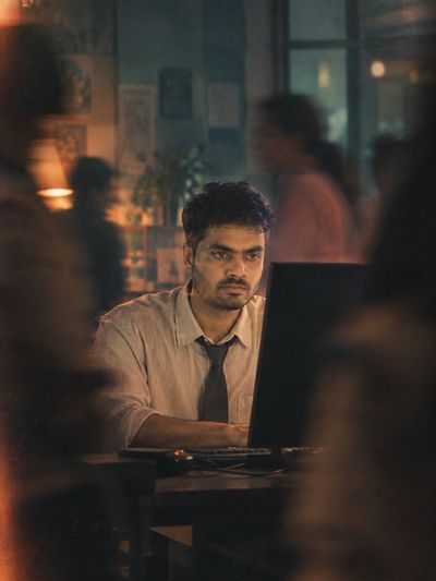 Man Lost in Work While Blurred Figures Pass By