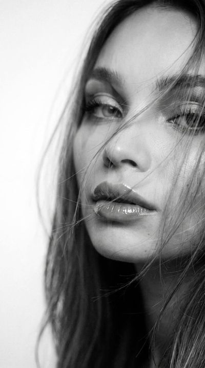 Wind-swept woman with glossy lips in dreamy double exposure