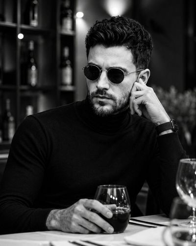 A contemplative gentleman in a turtleneck sips red juice