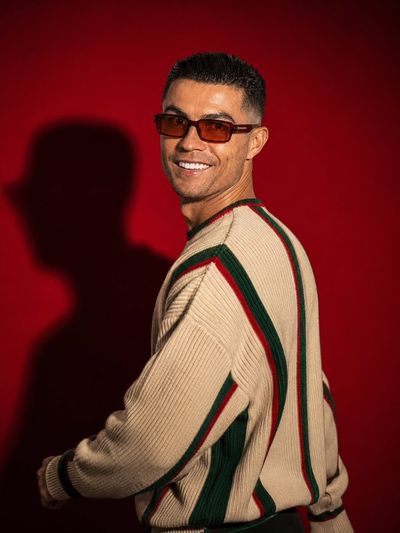 A model in a striped sweater glances back with a subtle confident smile.