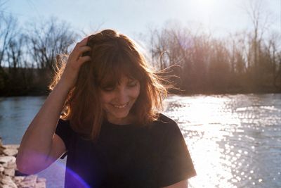 Young woman smiles warmly while running hand through windblown hair