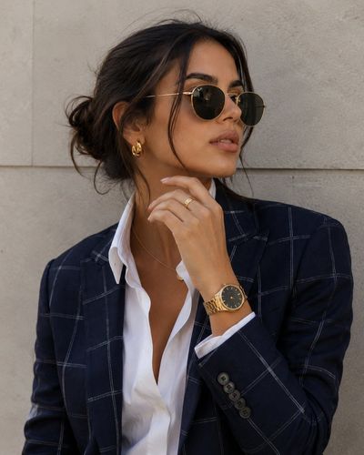 A stylish woman in a navy blazer gazes upward confidently.