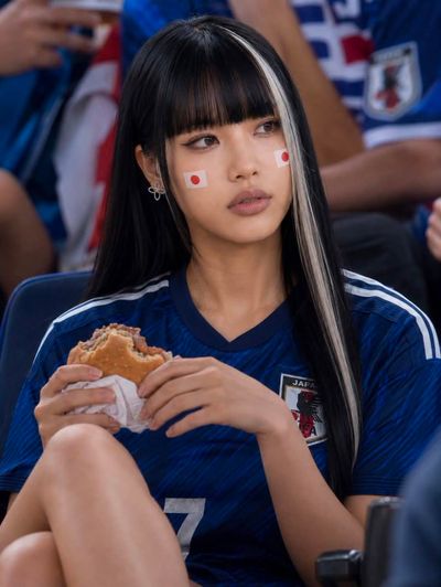 Japanese fan with platinum streak cheers at night football match
