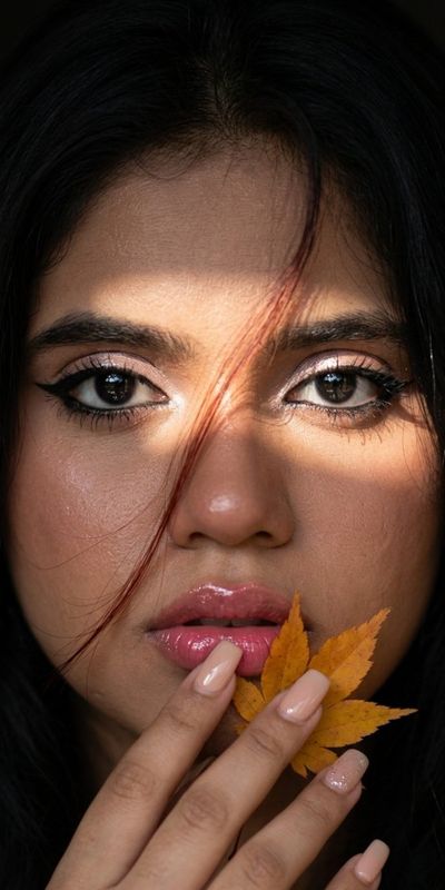 Autumn's golden leaf rests gently on her glossy lips