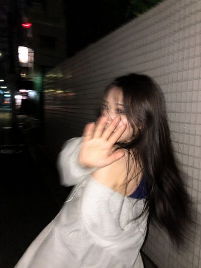 Blurred woman turns back with hand raised in Tokyo night
