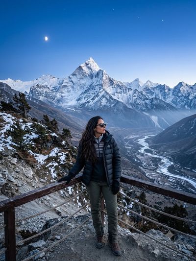 A lone hiker admires snow-capped peaks during twilight hours