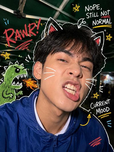 A young person in a blue windbreaker makes a playful rawr face
