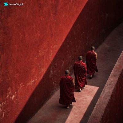 Three crimson-robed monks walk through a dusty red corridor