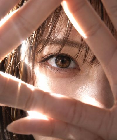 Extreme close-up of a Japanese eye peering through finger triangle