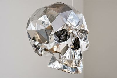 Metallic origami sculpture glows with silver reflections in a minimal void.