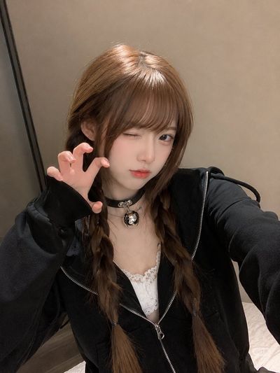 East Asian woman in black hoodie stares calmly into phone camera