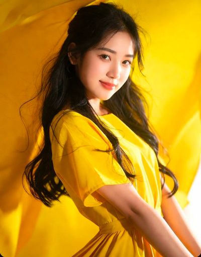 A young woman in a bright yellow dress glows under golden light.