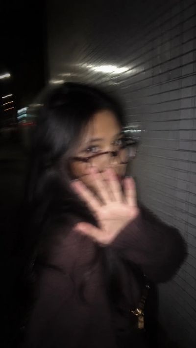 A young woman in a blue dress playfully hides her face from the camera.