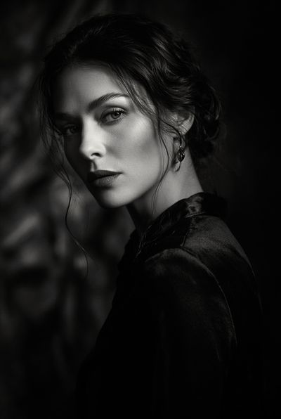 Woman gazes over shoulder in dramatic black-and-white chiaroscuro portrait