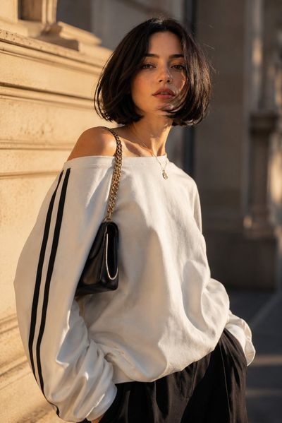 Young woman in oversized sweatshirt gazes upward in golden hour sunlight