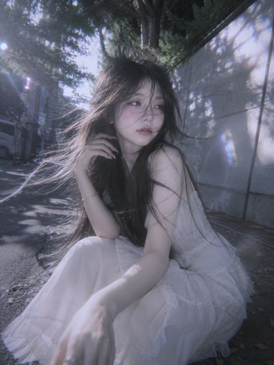 A shy doll-like woman feels the breeze in soft pastel tones