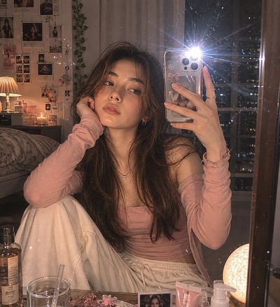 A young Korean woman captures her mirror selfie with a vintage camera flash