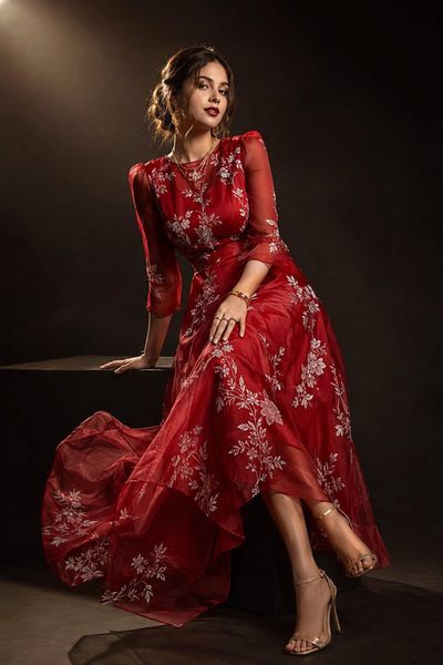 A model in ruby organza poses elegantly on black pedestal