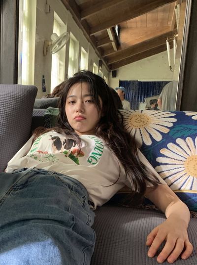 Tired young woman in oversized tee slumps on sofa after huge meal