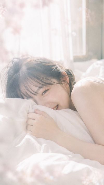 A young woman laughs shyly in soft morning light