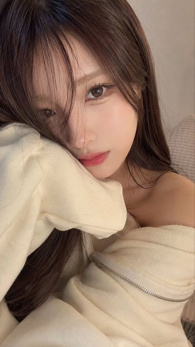 Young woman rests her cheek in a cozy cream hoodie sleeve