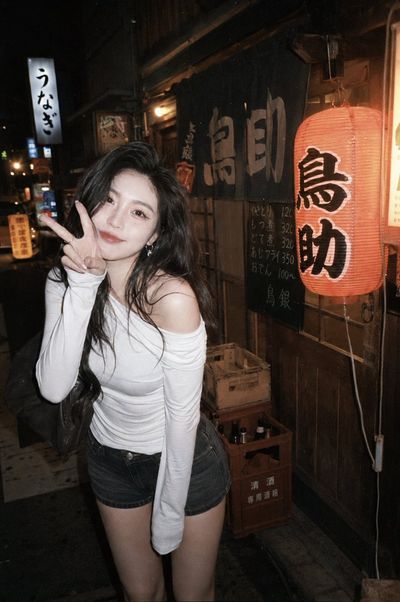 Young woman makes V-sign outside a warm Tokyo izakaya