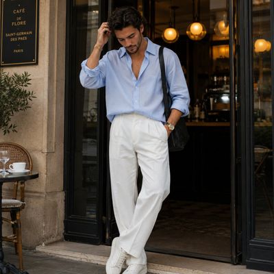 Dark-haired man leans in Parisian cafe doorway with effortless style