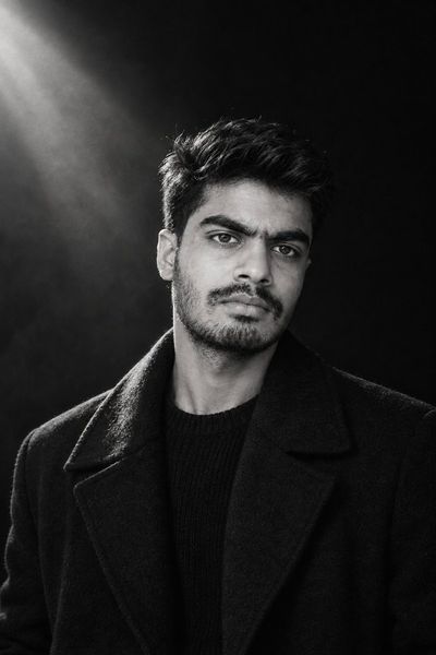 A young man emerges from darkness in striking black-and-white portrait
