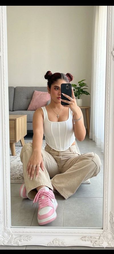 A woman takes a mirror selfie while posing on the floor