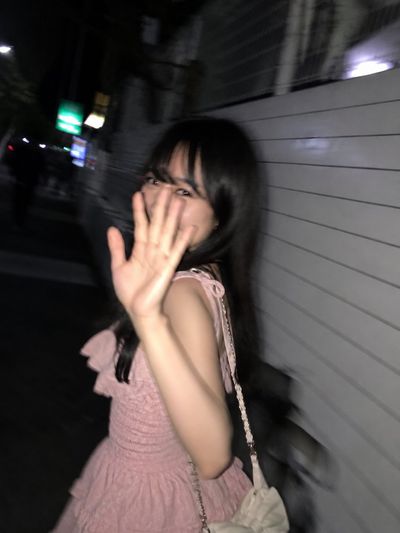 A shy woman turns back mid-walk under streaked Tokyo lights