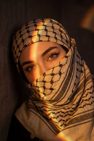 Mysterious keffiyeh-clad woman with striking eyes bathed in warm light