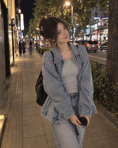 Young Woman Smiles While Holding Compact Camera On Night Street