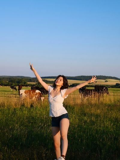 Joyful Woman Twirls in Sunlit Pasture with Grazing Cows