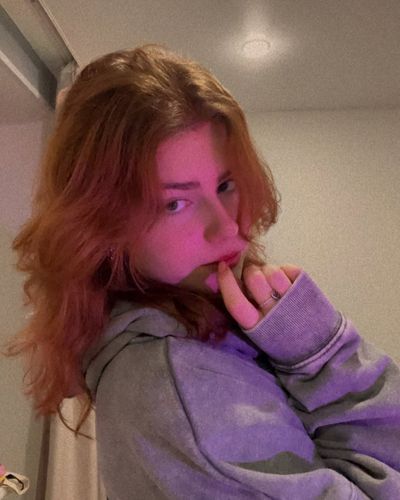 A woman rests her cheek on her hand in a blue car