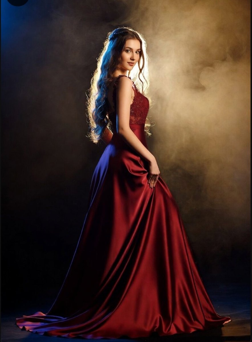 A crimson gown catches the golden backlight in a smoky room.