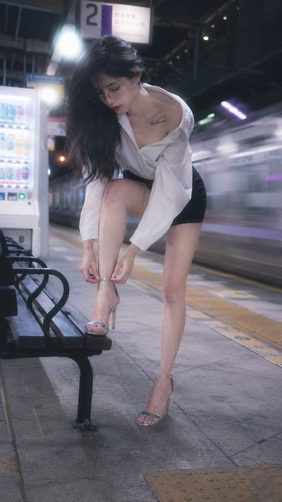 Idol bends to fasten her heel on a quiet platform