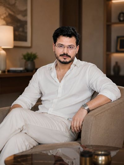 A confident man in a white shirt stands in a luxurious living room.