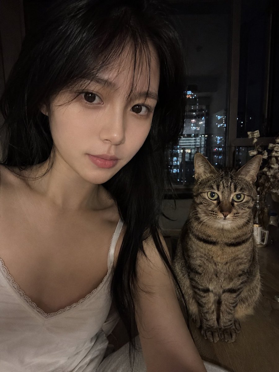 Young woman in white lace top shares quiet night with tabby cat