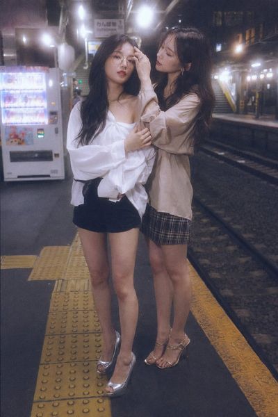 Two women share a tender moment on a quiet train platform