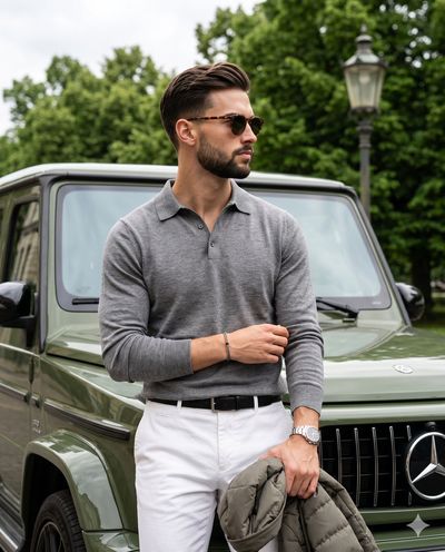 Man in heather grey leans against a glossy olive-green G63.