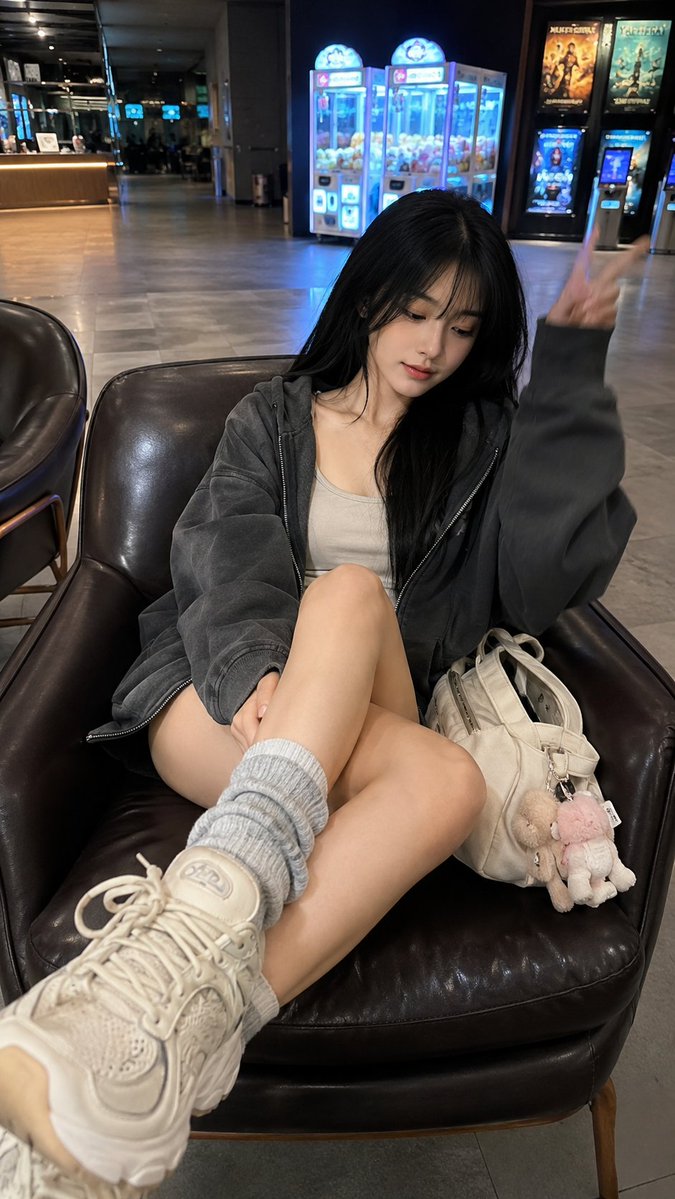 Young woman in oversized hoodie poses in cinema lobby