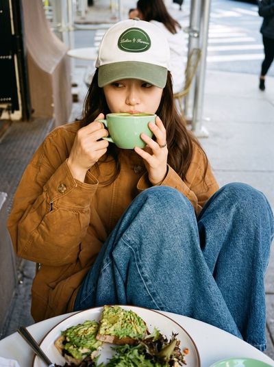 Woman in cap sips matcha at sunny city cafe