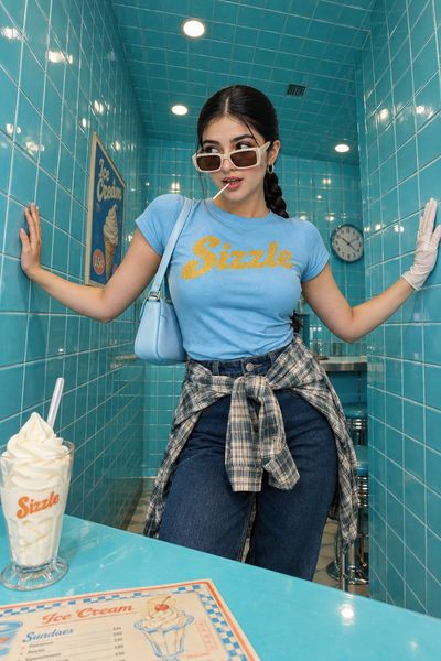 Confident woman poses in turquoise tiled diner with retro flair