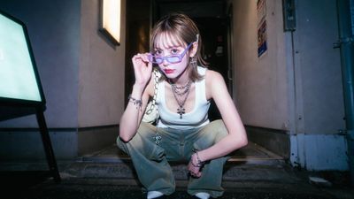 A woman squats at a Kabukicho bar entrance pulling down her glasses