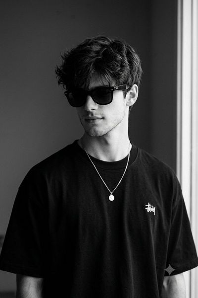 Young man in black sunglasses poses with confident streetwear style